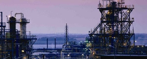 A chemical processing plant near a body of water at twilight